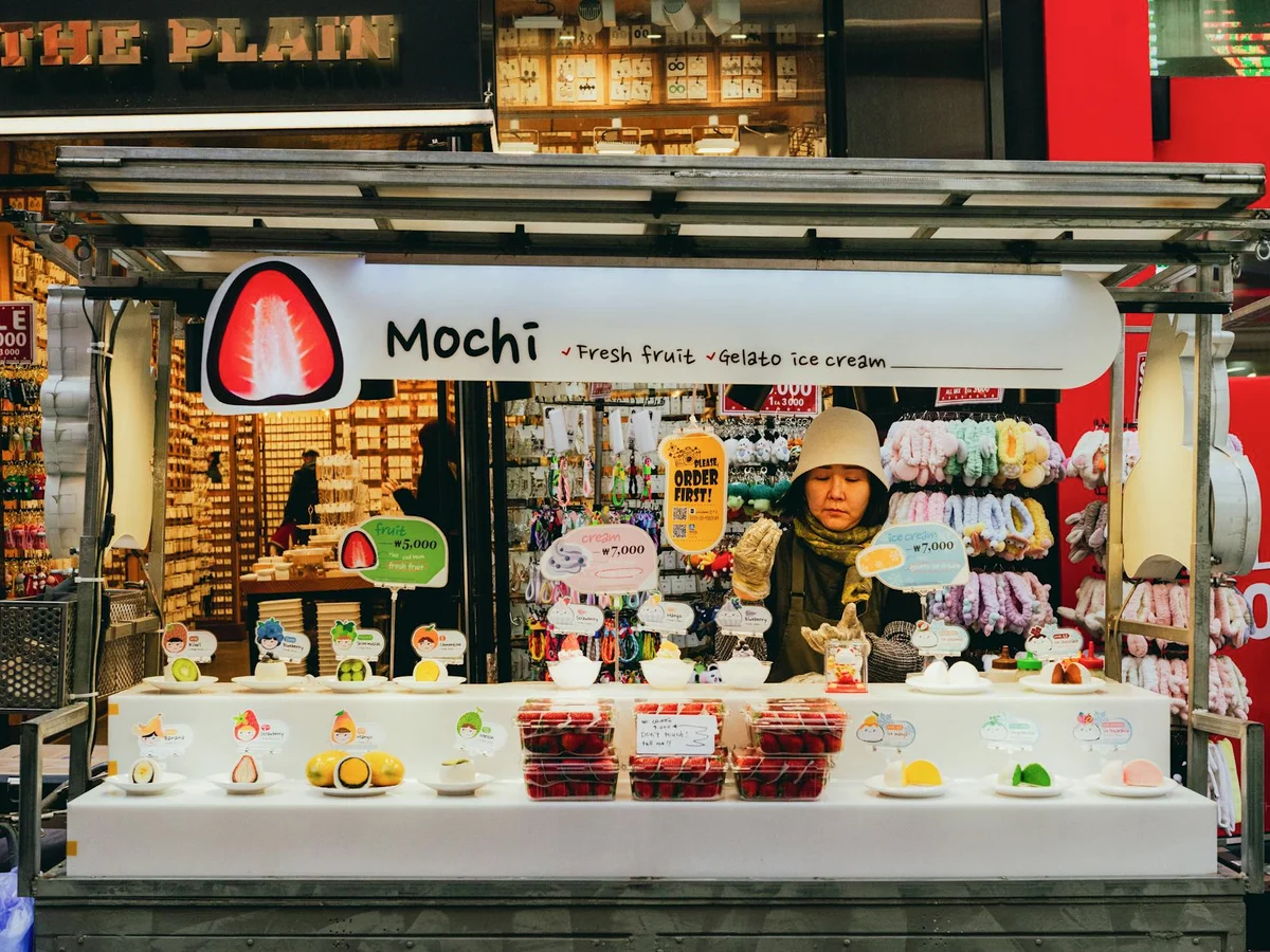 Colorful mochi stall at Seoul street market showcasing fresh fruit and gelato. Captivating urban scene.